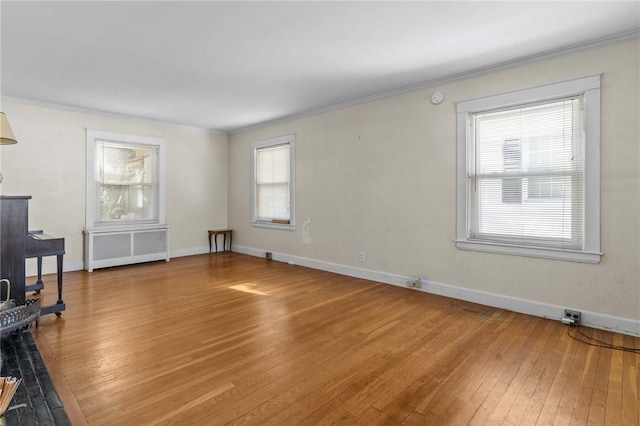 unfurnished living room featuring crown molding, radiator heating unit, and hardwood / wood-style flooring