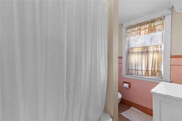 bathroom with tile walls, tile patterned flooring, and toilet