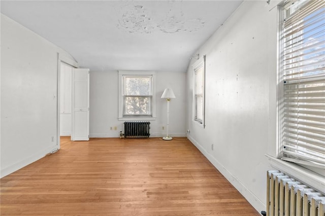 unfurnished living room featuring radiator and light hardwood / wood-style flooring