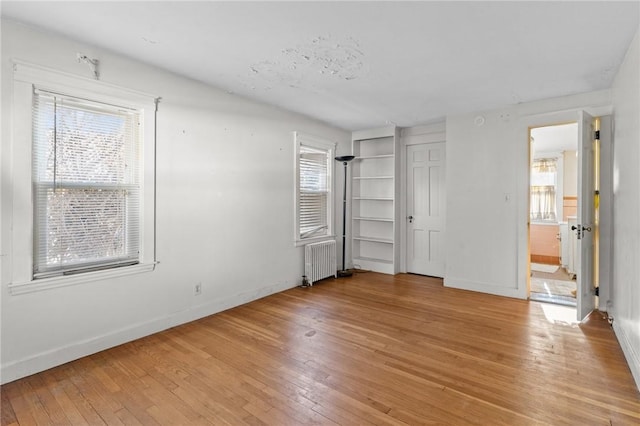 unfurnished bedroom featuring radiator heating unit and light hardwood / wood-style floors