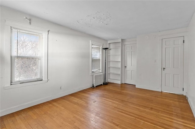 unfurnished bedroom featuring radiator and light hardwood / wood-style floors