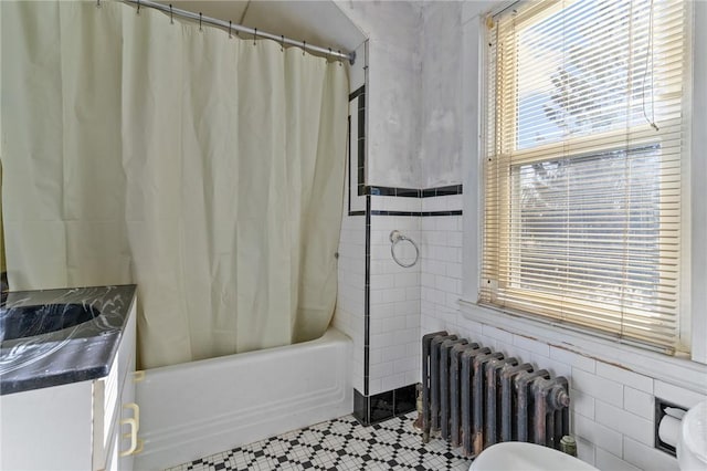 bathroom featuring vanity, radiator, tile walls, and shower / bath combo with shower curtain