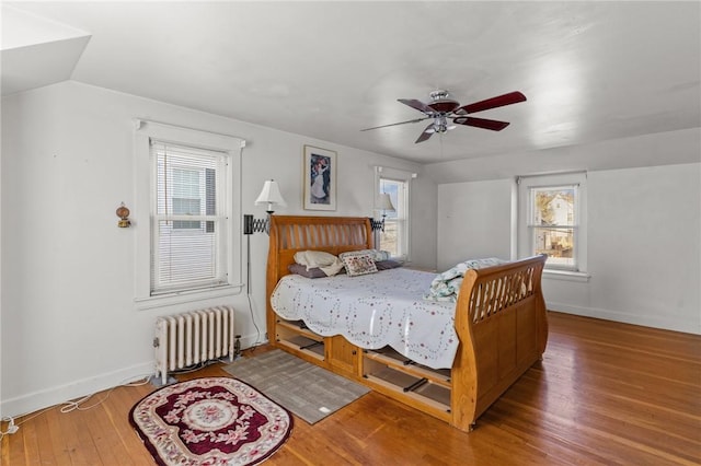 bedroom with hardwood / wood-style flooring, ceiling fan, radiator heating unit, and vaulted ceiling