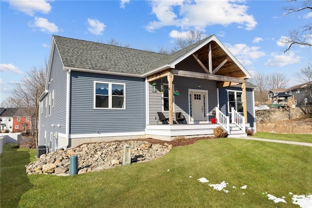 view of front of home with a porch, a shingled roof, and a front yard