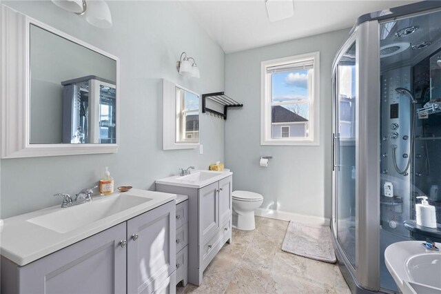 full bath with a sink, toilet, two vanities, and a shower stall