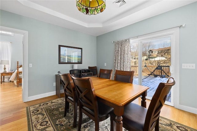 dining area with light hardwood / wood-style flooring and a tray ceiling