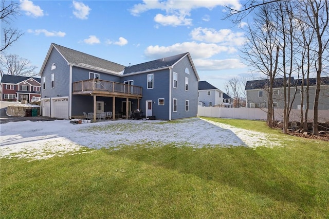 rear view of property featuring a wooden deck, a garage, and a lawn