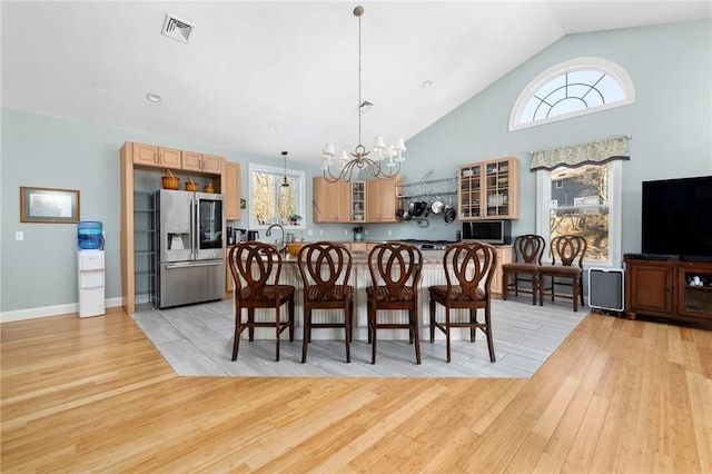 dining area featuring sink, light hardwood / wood-style flooring, high vaulted ceiling, and a chandelier