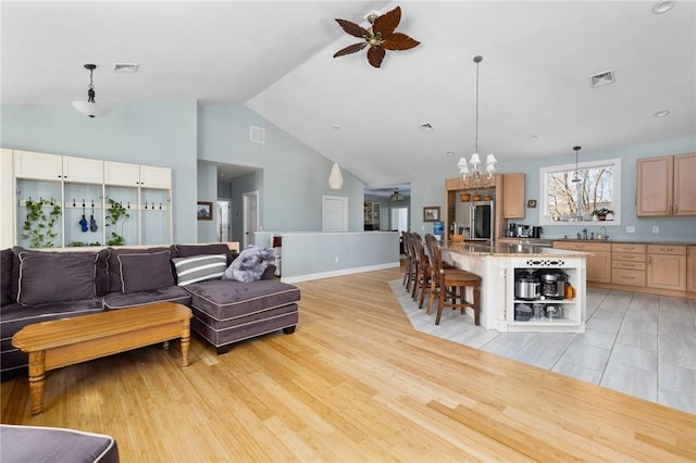 living room with high vaulted ceiling, ceiling fan with notable chandelier, and light hardwood / wood-style floors