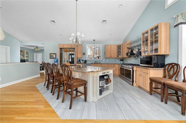 kitchen with visible vents, a center island, light brown cabinetry, a kitchen breakfast bar, and stainless steel appliances