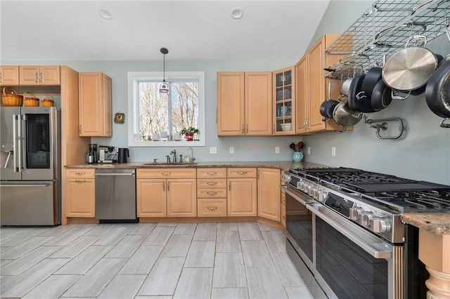 kitchen featuring stainless steel appliances, decorative light fixtures, light brown cabinetry, and stone countertops