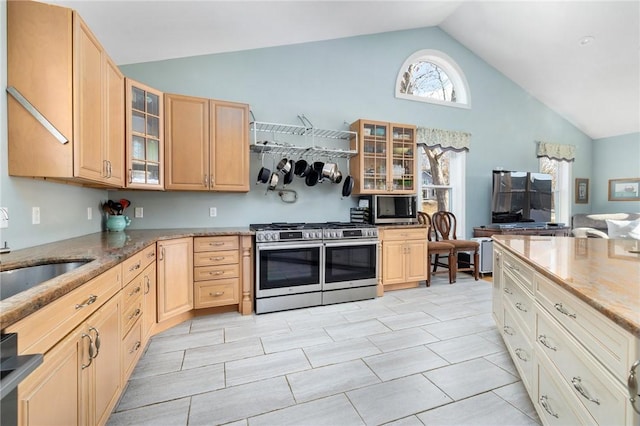 kitchen with lofted ceiling, light brown cabinetry, sink, dishwashing machine, and range with two ovens