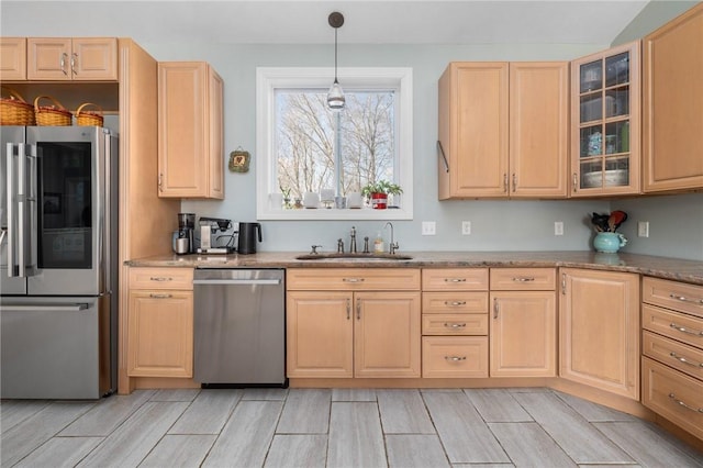 kitchen with stainless steel appliances, decorative light fixtures, light brown cabinetry, and sink