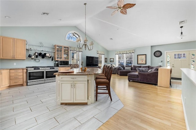 kitchen featuring a kitchen bar, a center island, light brown cabinets, pendant lighting, and stainless steel appliances