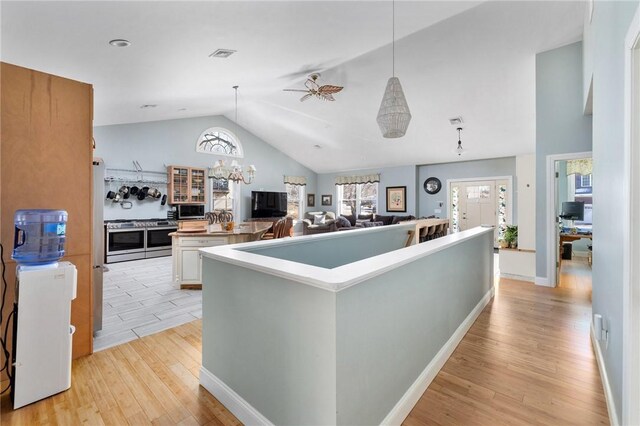 kitchen featuring visible vents, light wood finished floors, lofted ceiling, hanging light fixtures, and a large island