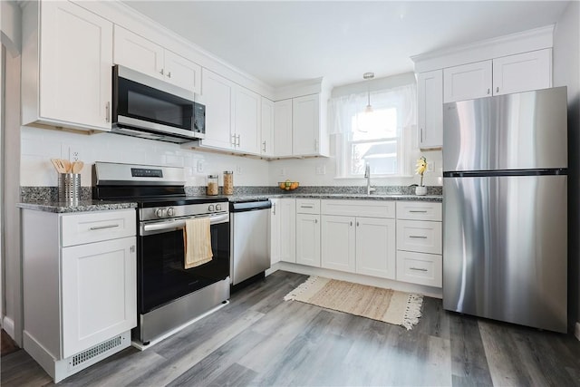 kitchen with dark hardwood / wood-style flooring, pendant lighting, stainless steel appliances, and white cabinets