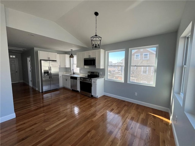 kitchen featuring appliances with stainless steel finishes, pendant lighting, white cabinetry, sink, and dark hardwood / wood-style flooring