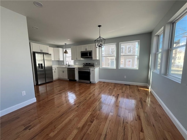 kitchen with pendant lighting, sink, white cabinetry, stainless steel appliances, and dark hardwood / wood-style floors