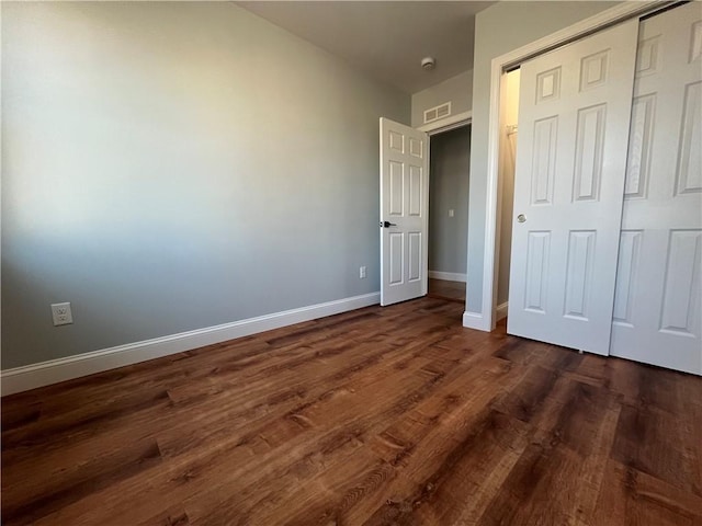 unfurnished bedroom with dark wood-type flooring and a closet