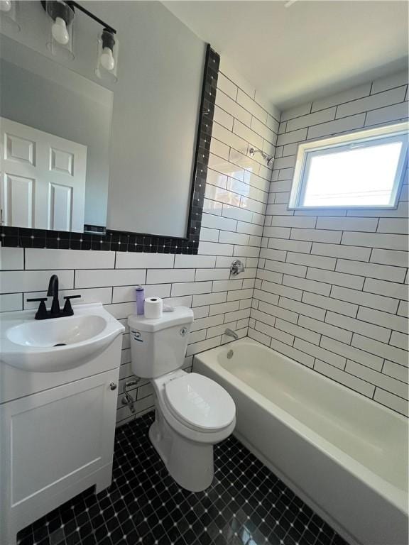 full bathroom featuring toilet, tile walls, vanity, tiled shower / bath combo, and backsplash