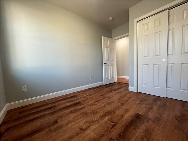 unfurnished bedroom with dark hardwood / wood-style floors and a closet