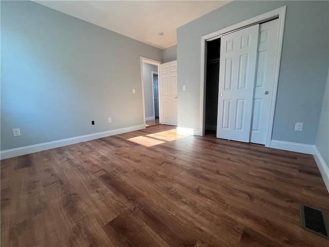 unfurnished bedroom with dark hardwood / wood-style flooring and a closet