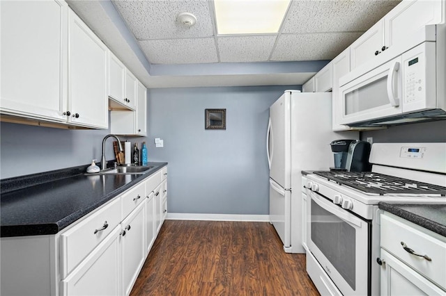 kitchen with sink, white appliances, dark wood-type flooring, a paneled ceiling, and white cabinets