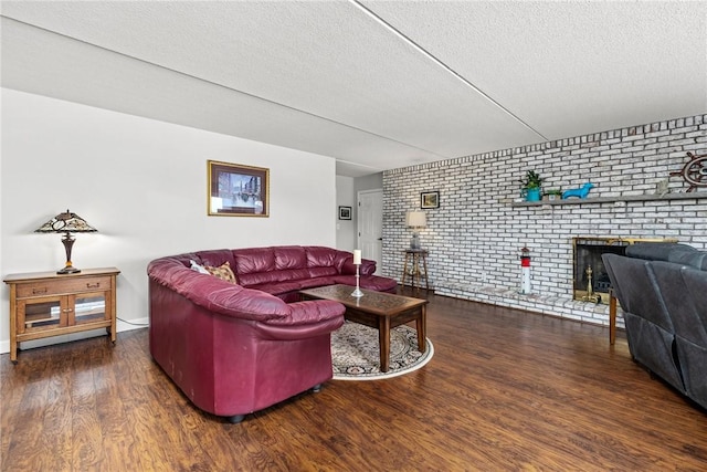 living room featuring brick wall, dark hardwood / wood-style flooring, a brick fireplace, and a textured ceiling