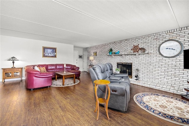 living room featuring brick wall, dark hardwood / wood-style flooring, a brick fireplace, and a textured ceiling