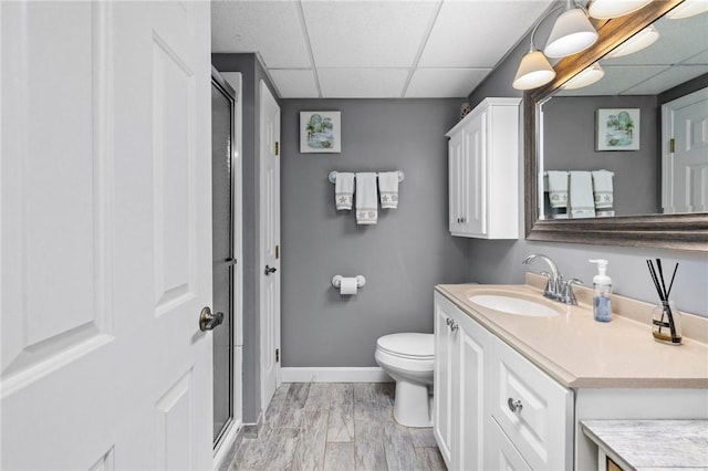 bathroom with vanity, toilet, a paneled ceiling, and a shower with shower door