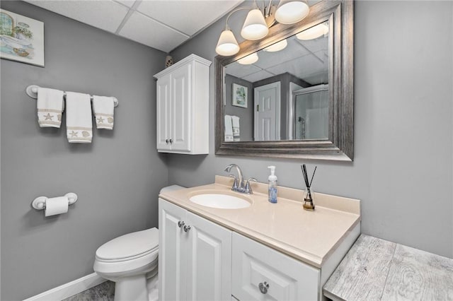 bathroom featuring a shower with door, vanity, a paneled ceiling, and toilet