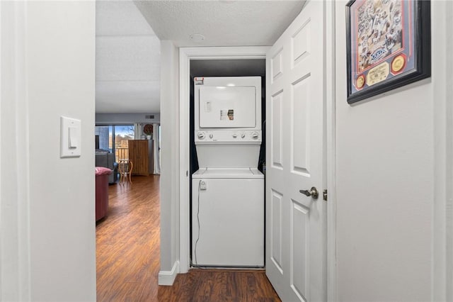 laundry room featuring dark hardwood / wood-style floors, stacked washer and clothes dryer, and a textured ceiling