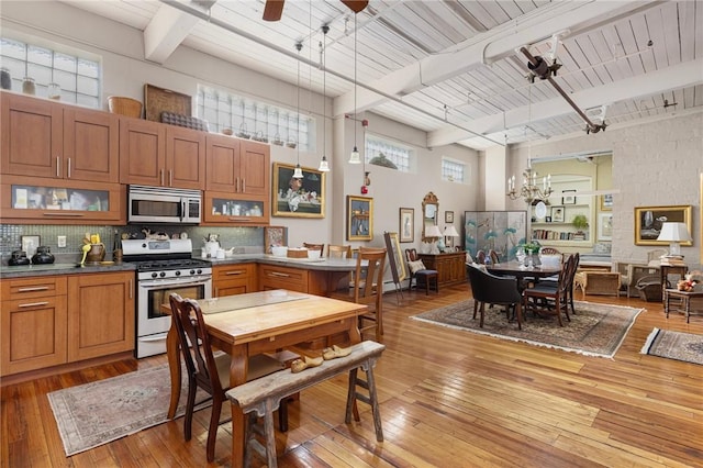 kitchen featuring pendant lighting, appliances with stainless steel finishes, hardwood / wood-style floors, wooden ceiling, and beamed ceiling