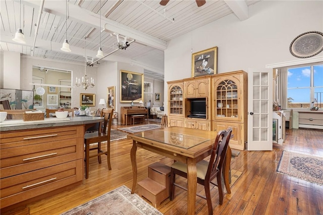 dining room featuring beamed ceiling, ceiling fan with notable chandelier, hardwood / wood-style floors, and wooden ceiling