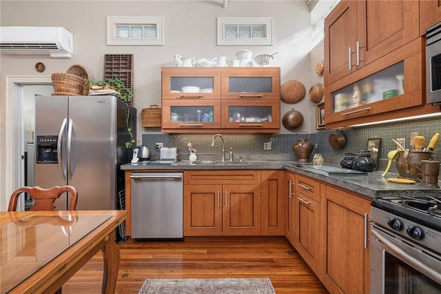 kitchen with backsplash, appliances with stainless steel finishes, sink, and an AC wall unit