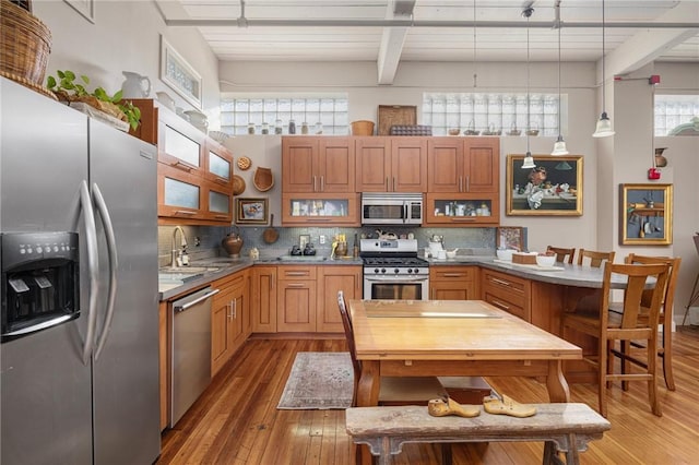 kitchen with a towering ceiling, pendant lighting, sink, decorative backsplash, and stainless steel appliances