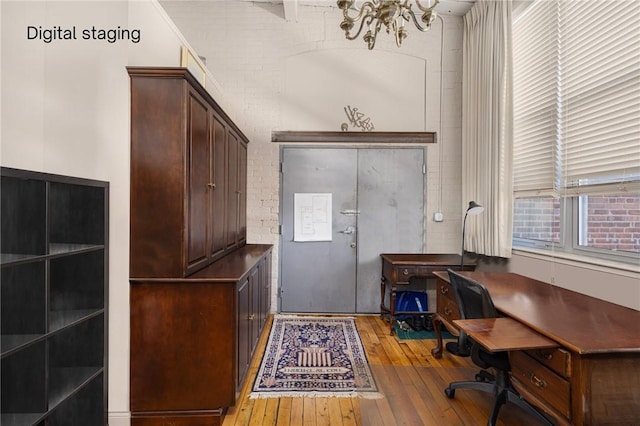 office featuring light hardwood / wood-style floors, a chandelier, and brick wall