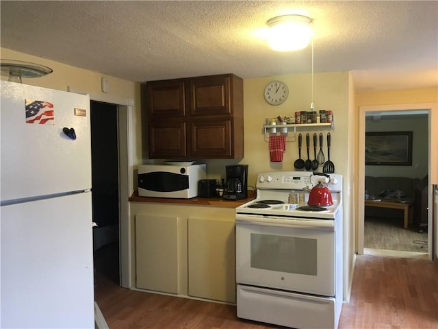 kitchen with hardwood / wood-style floors, white appliances, and a textured ceiling