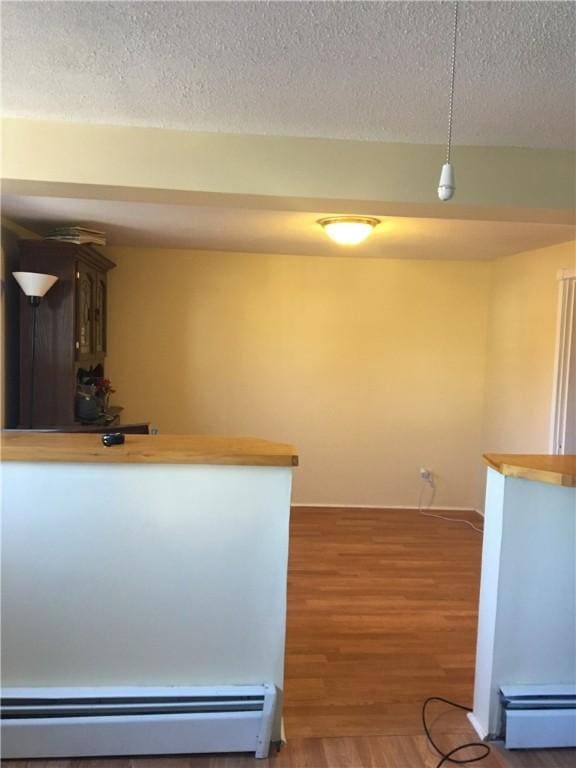 kitchen with a baseboard radiator, dark wood-type flooring, a textured ceiling, and decorative light fixtures