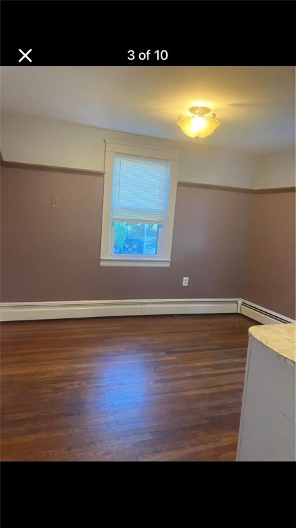 unfurnished room with a baseboard radiator and dark hardwood / wood-style flooring