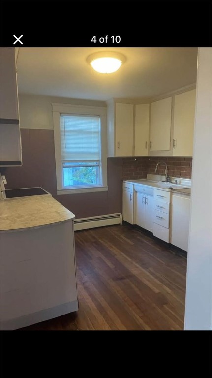 kitchen featuring dark wood-type flooring, sink, tasteful backsplash, a baseboard radiator, and white cabinets