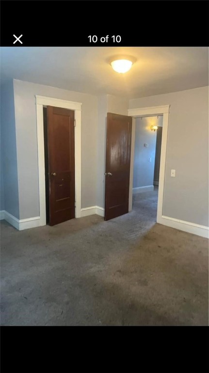 unfurnished room featuring dark colored carpet