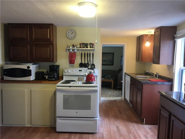 kitchen with white appliances, sink, hardwood / wood-style floors, and a textured ceiling