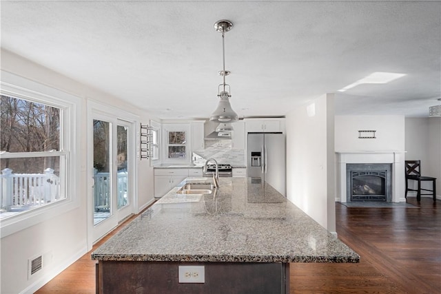 kitchen with sink, light stone counters, hanging light fixtures, stainless steel appliances, and white cabinets