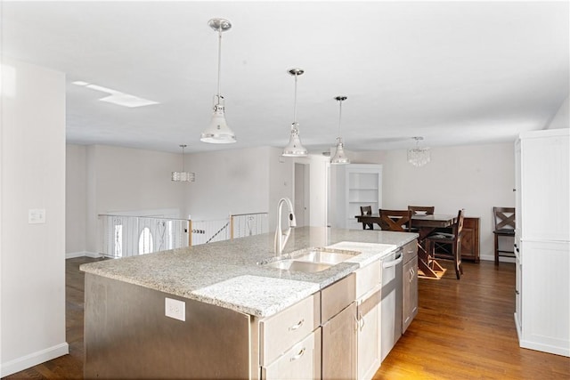 kitchen with sink, pendant lighting, light stone counters, hardwood / wood-style flooring, and a kitchen island with sink