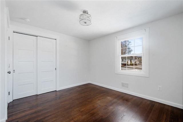 unfurnished bedroom with dark hardwood / wood-style flooring and a closet