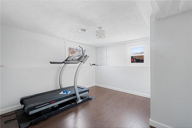 exercise room featuring dark hardwood / wood-style floors and a textured ceiling