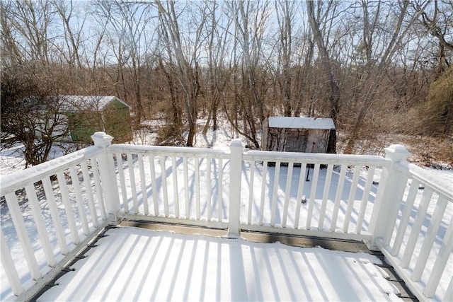 snow covered deck featuring a storage shed