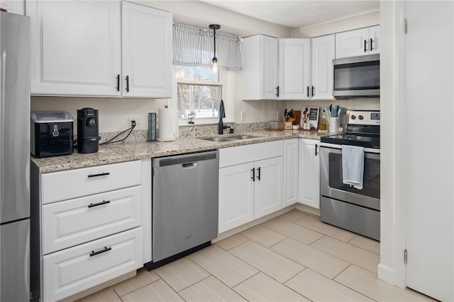 kitchen featuring sink, white cabinetry, pendant lighting, stainless steel appliances, and light stone countertops