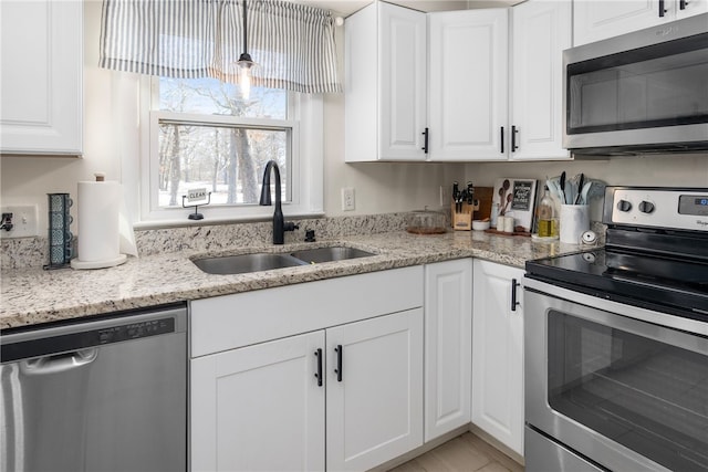 kitchen featuring pendant lighting, sink, stainless steel appliances, light stone counters, and white cabinets